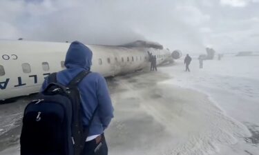 People evacuate from an overturned Delta Connection CRJ-900 aircraft