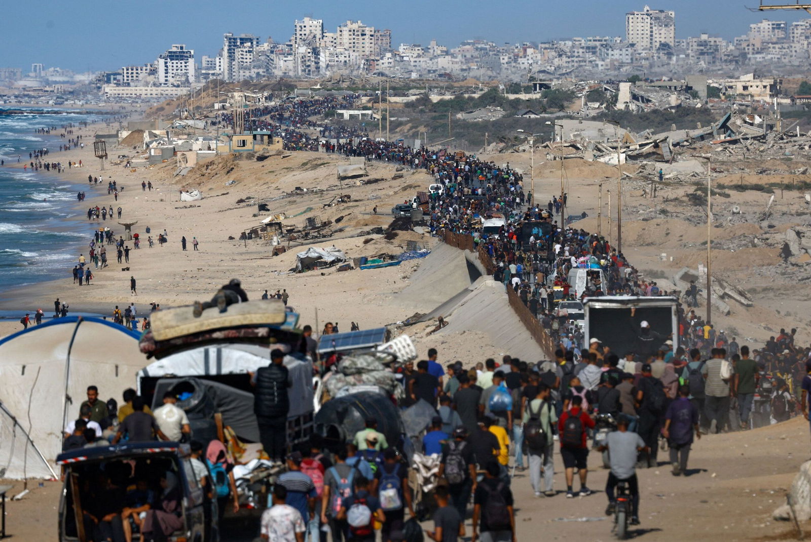 <i>Yousef Al Zanoun/AP via CNN Newsource</i><br/>Displaced Palestinians wave to the camera as they walk along the coastal road in the direction of Gaza City on October 10.